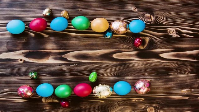 Easter colored eggs, large and small, are laid out on a table in two parallel rows. Colorful pastel easter eggs on wooden board background with space vintage toned.