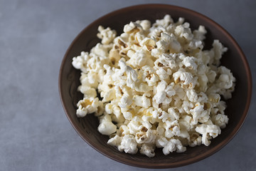 Popcorn in brown bowl on a gray background.