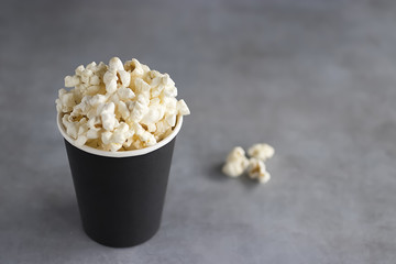 Popcorn in black paper cup on a gray background