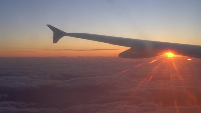 Real Sunrise Over Clouds, with sun appearing under the wing of Airplane, with Beautiful Orange Tones