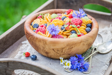 Closeup of cornflakes with berry fruits in wooden bowl