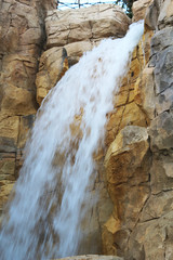 Artificial waterfall in the golden rocks. Beautiful construction. Freshness among the stones