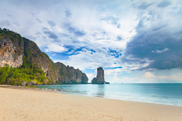 Stunning scene the limestone cliffs covered with the vegetation and the ocean shore on the cloudy sky background. Beauty of wild virgin Thai nature. Ideal place for the calm rest.