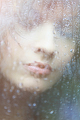 Attractive woman looking out of the window on rainy day