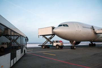 Airport bus near the passenger airplane on which the catering truck delivers food