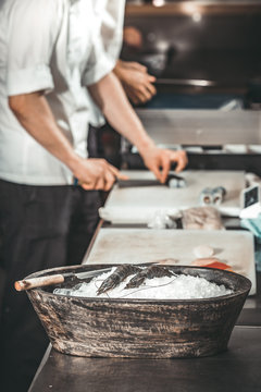 The wooden bowl with the freshly caught prawns put on the ice. The chef making the delicious sushi background. Stylish kitchen interior of the modern restaurant. Healthy food concept.