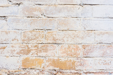 Textured background of old yellow brickwork covered with cracked and partially falling off whitewash. Nice brick background in kraft style