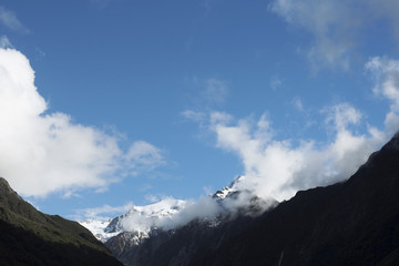Paisaje de picos de montañas nevados y verdes con cielo nublado en Nueva Zelanda