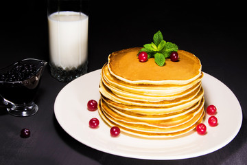 Delicious breakfast of fresh baked pancakes with milk, blueberry jam and fresh cranberry