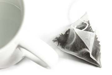 Single bag of elite tea in silk fabric packing and tea mug. Small depth of sharpness.