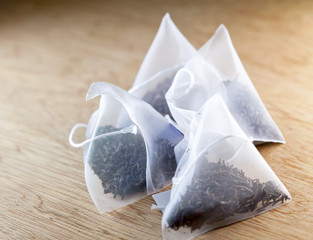 bags of elite tea in silk fabric packing on a wooden background