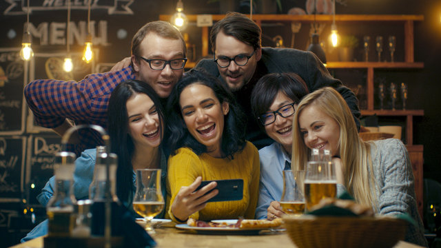In the Bar/ Restaurant Hispanic Woman Takes Selfie of Herself and Her Best Friends. Group Beautiful Young People in Stylish Establishment.