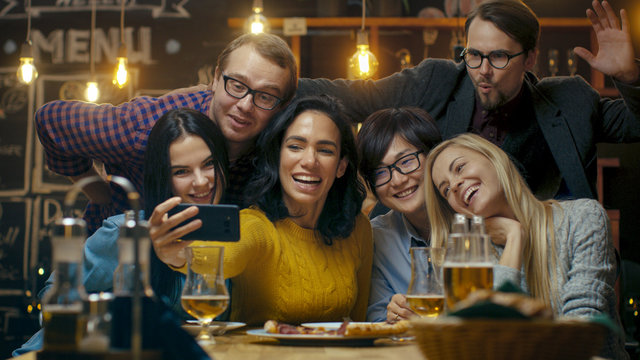 In the Bar/ Restaurant Hispanic Woman Takes Selfie of Herself and Her Best Friends. Group Beautiful Young People in Stylish Establishment.