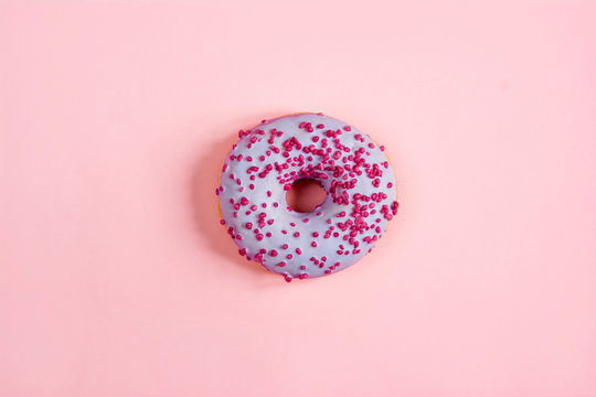purple round donut on the center of a pink background