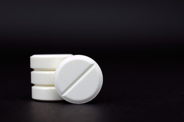 white round tablets painkiller copy space, black background, selective focus