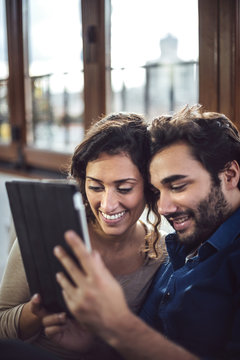 Young Couple Sitting On Sofa Using Digital Tablet