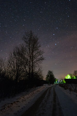 The road in Russian village , frosty and snowy at night. The trees and the starry sky overhead. The...