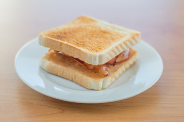 Toast with fried bacon on white plate.