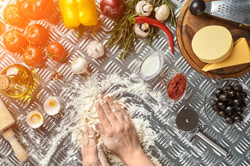 Pizza dough with ingredients on iron background, shot from above. Sun flare