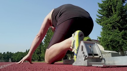 A  100m dash man sprinter starting from the blocks on a tartan at a stadion. Reday, set, go. Slowmotion