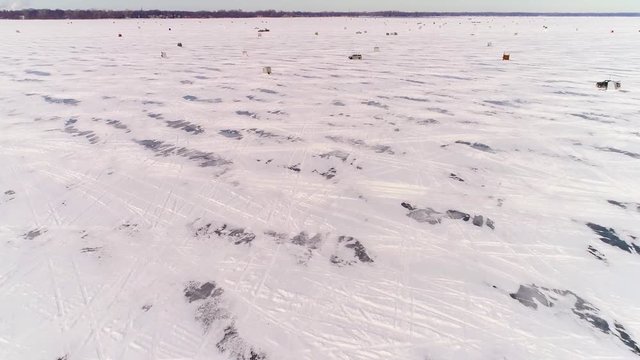 A community of ice huts in ice fishing and Sturgeon Spearing season on Lake Winnebago, Wisconsin, time lapse aerial flyover.