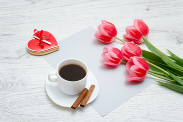 Fototapeta na wymiar Red gingerbread, pink tulips and mug of coffee. Light wooden background.