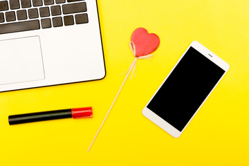 symbol heart  smartphone laptop. A decorative heart on  yellow background together  gadgets.