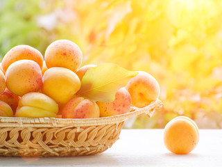 Wicker basket apricot on a green background, sunlight
