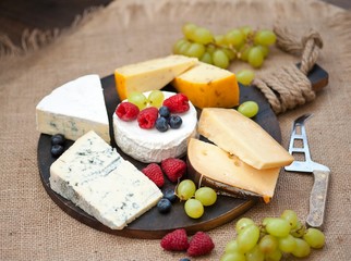 Cheese platter with different cheese and grapes and berries