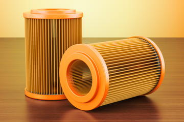 Set of car oil filters on the wooden table. 3D rendering