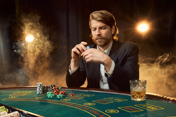 A man in a business suit sitting at the game table. Male player. Passion, cards, chips, alcohol,...
