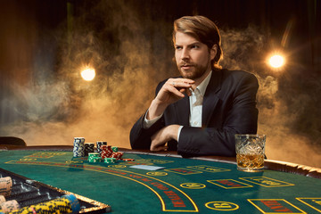 A man in a business suit sitting at the game table. Male player. Passion, cards, chips, alcohol,...