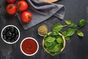 Italian cuisine. Mediterranean cuisine. Tomato, spinach leaves, oregano, tomato sauce and olives on table. Recipe Ingredients.