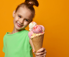 Pretty baby girl kid eating licking banana and strawberry ice cream in waffles cone