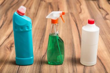 Bottles and spray products for household cleaning on the wooden floor. Cleaning concept.