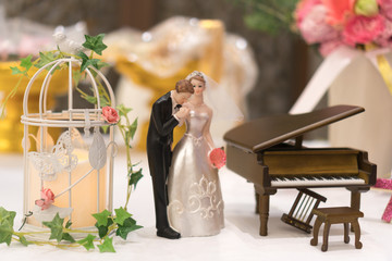 Miniature wedding couple doll with piano simulation wedding decoration on white table.wedding bride and groom couple doll in wedding reception.