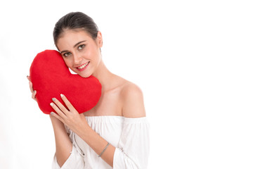 Happy beautiful young woman holding red cushion heart shape smiling isolated in white background and looking at camera with copyspace.love romance and valentines day concept.