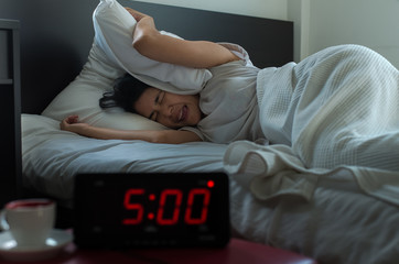 Young asian woman hates getting stressed waking up early 5 o'clock,Alarm clock