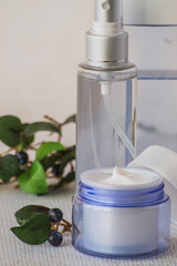 Cosmetic means for skin care of face and body. A small jar of cream and a bottle of lotion on a light background. 