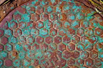Old rusty manhole with traces of blue peeling paint.