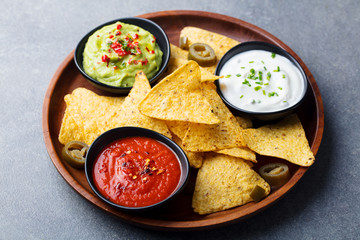 Nachos chips with dip variety on a wooden plate