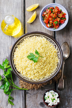 Couscous in bowl. Wooden background. Top view.