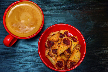 fresh aromatic coffee in a red mug and delicious pastry on a black wooden background