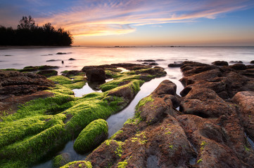 view of beautiful sunset with rocks covered by green moss at Kudat, Sabah Malaysia. image contain soft focus due to long expose.