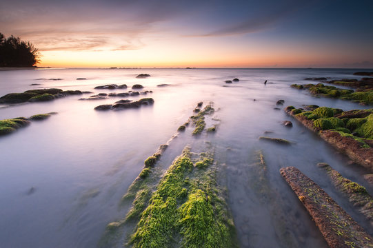 view of beautiful sunset with rocks covered by green moss at Kudat, Sabah Malaysia. image contain soft focus due to long expose.
