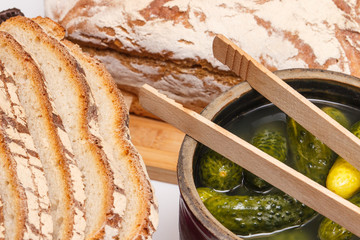 Fresh baked homemade traditional rye or wheat bread and pickled cucumbers in clay pot