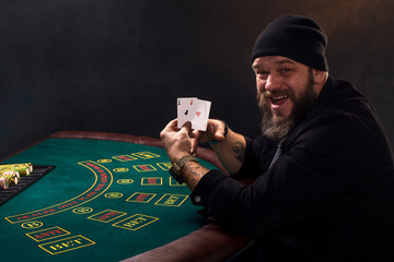 Bearded man showing poker cards on black background