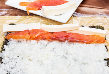 Making sushi roll with red fish.