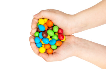 Child holding many colorful round candies in her palms. Isolated on white. Top view.