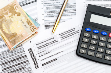 Money, calculator and pen on the German tax form. Top view. 